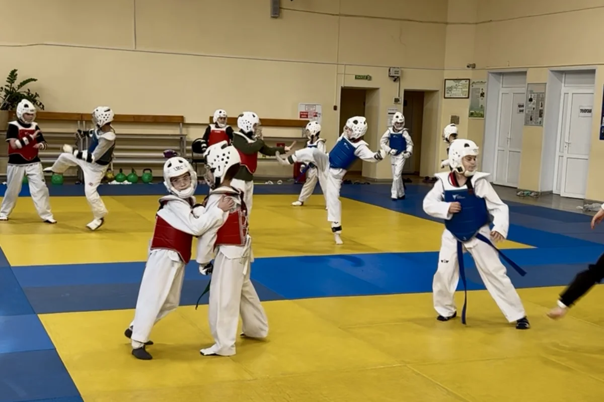 Спарринги в защитной экипировке на тренировке тхэквондо